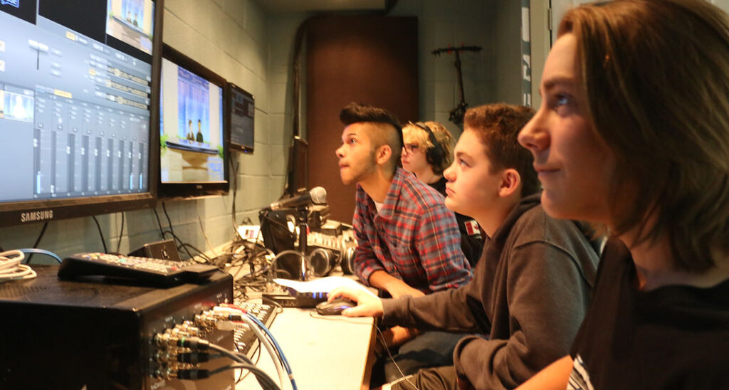 Students working at sound board with microphones.