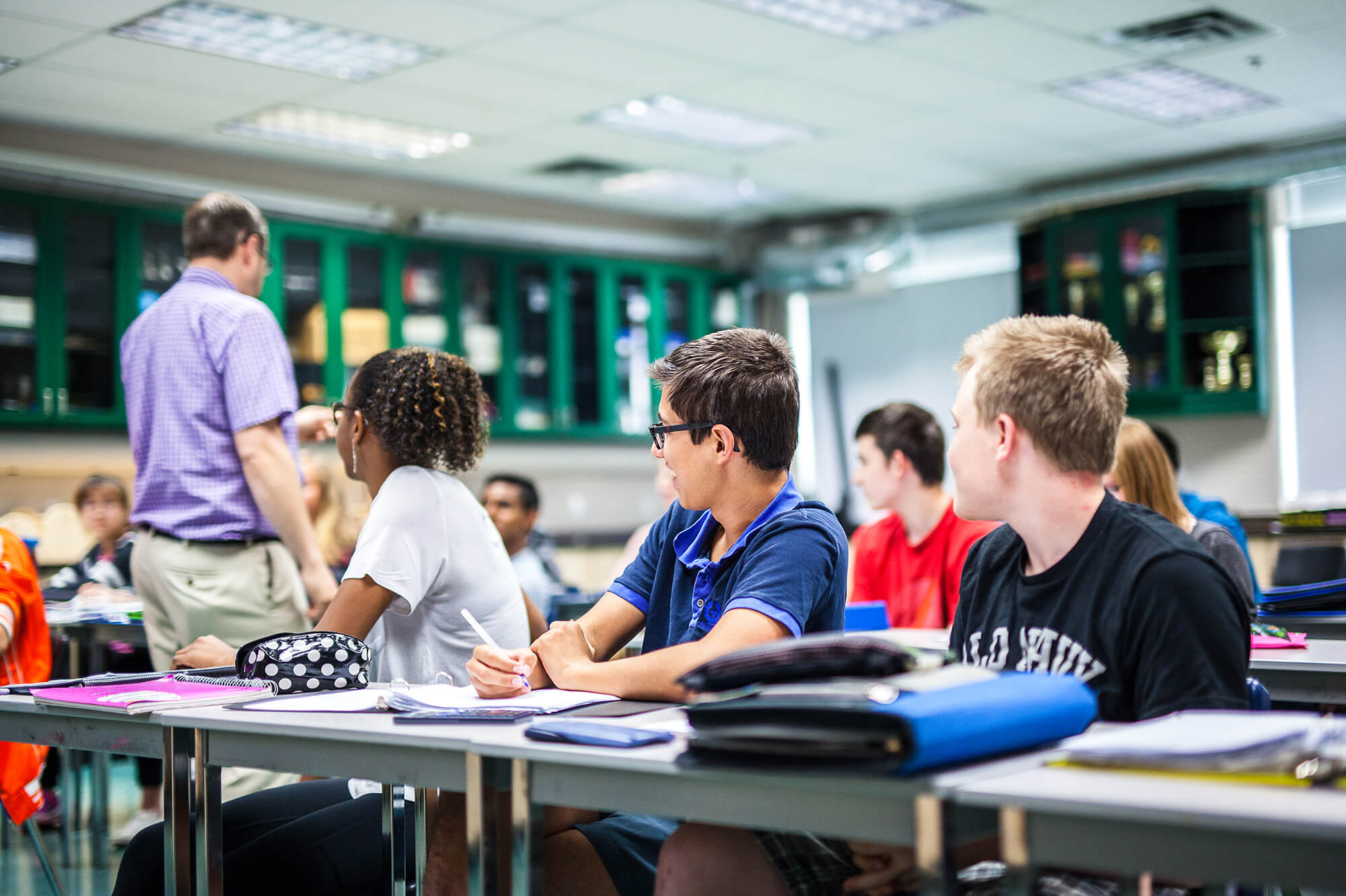 A classroom full of students listening to the teacher.