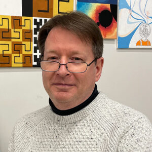 Photo of a man wearing glasses and a sweater