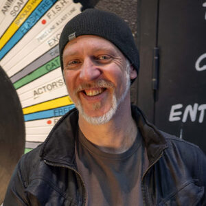 Photo of a man smiling, wearing a toque and a leather jacket