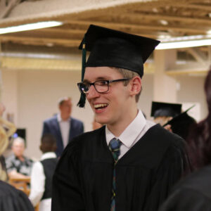 Happy Student wearing graduation cap and gown at an assembly