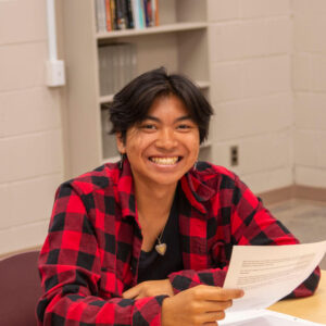 Smiling student at desk holding school work assignment