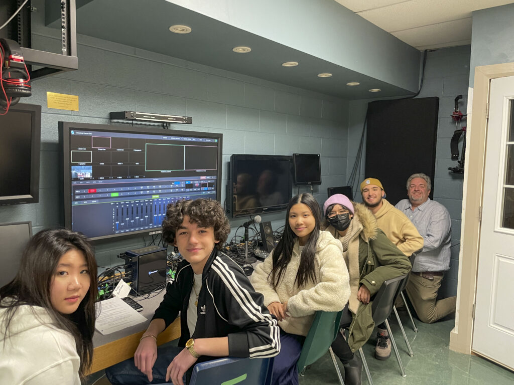 Students smiling in front of computers
